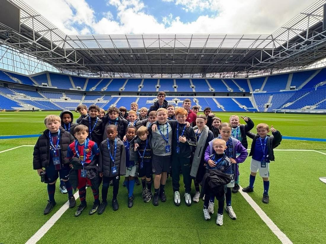 A large group of young players together on the pitch at a stadium