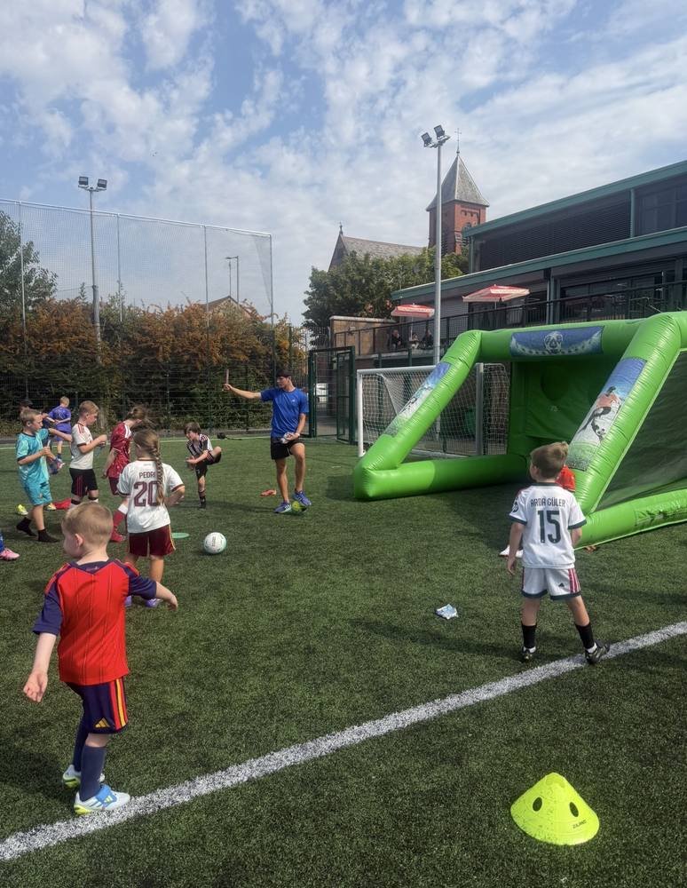 Children playing games at a training session with an inflatable goal